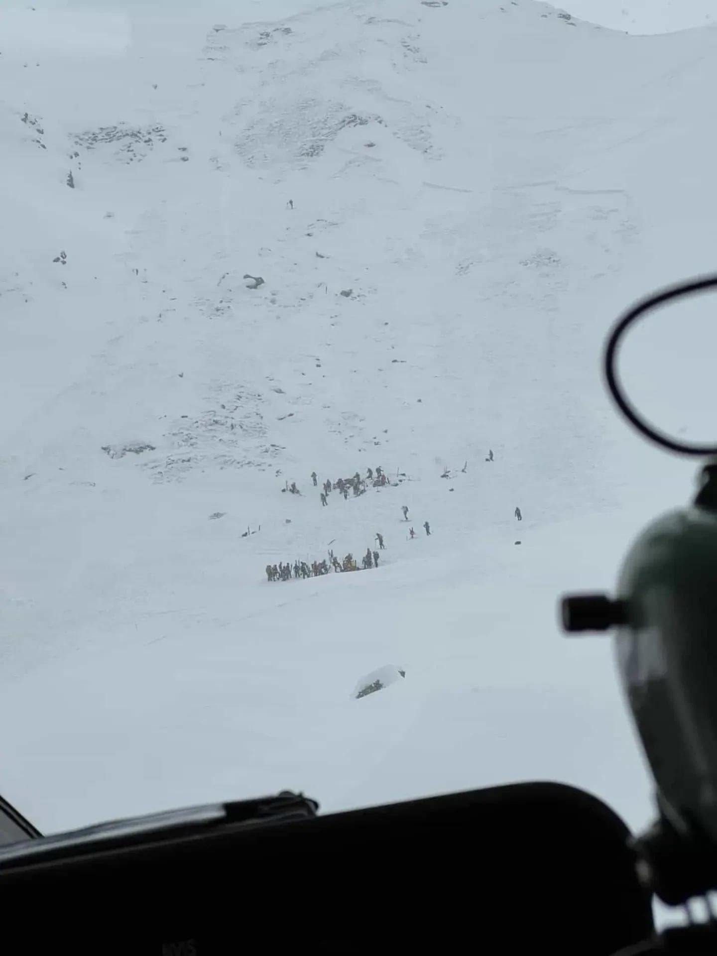The avalanche spot high in the mountains with rescue crews working the scene.