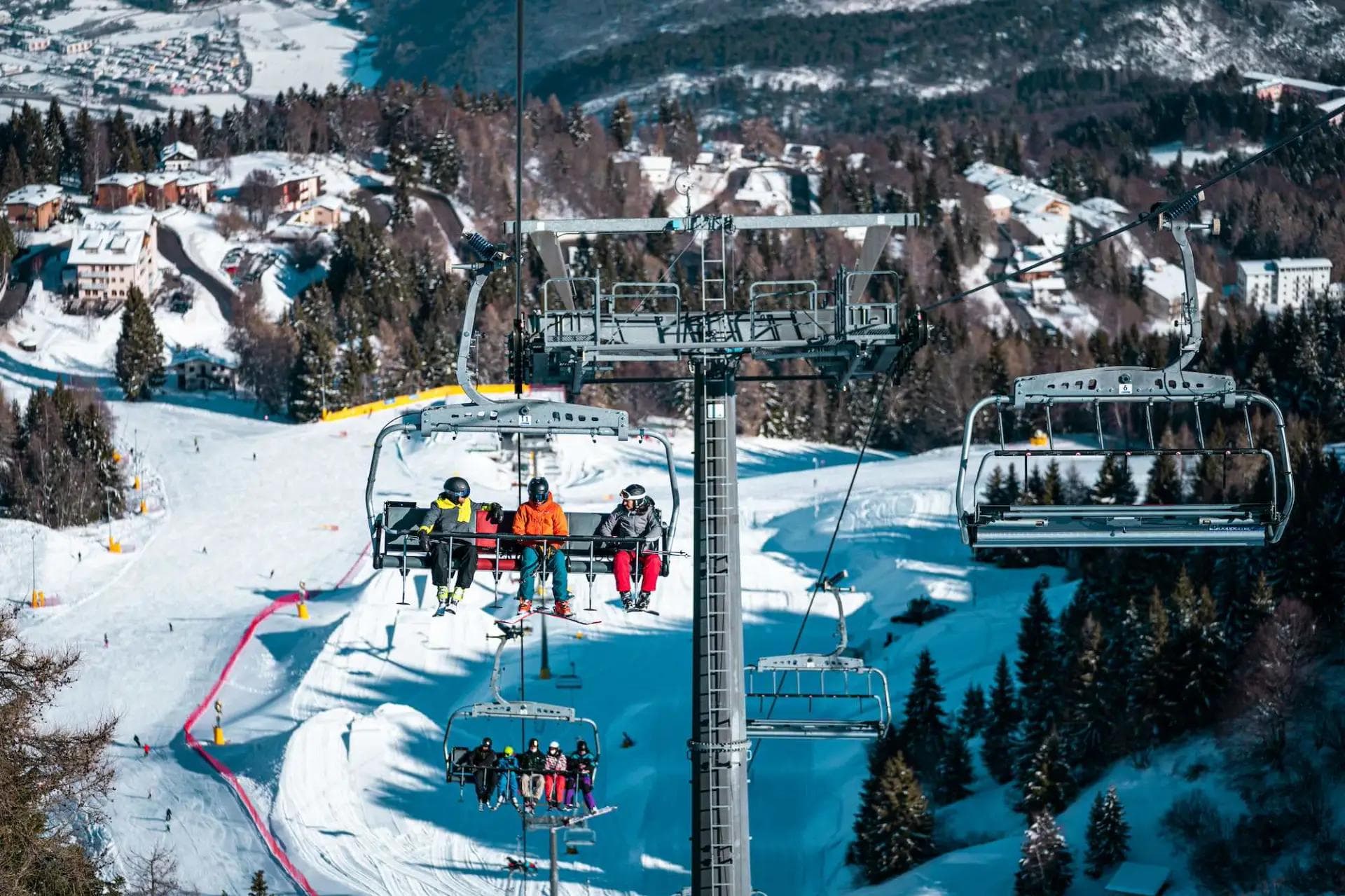 Skiers on a chairlift at Monte Bondone ski resort.
